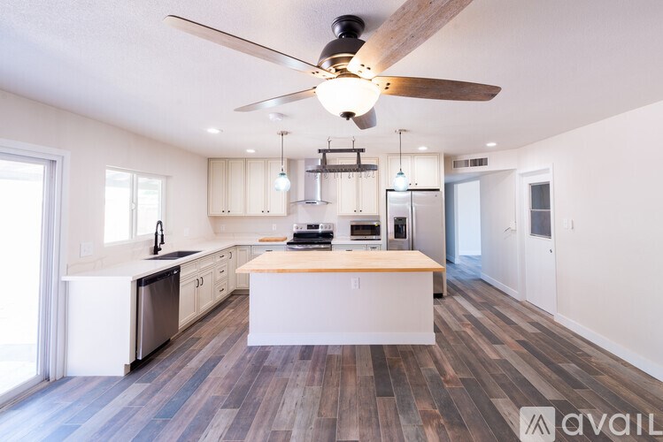 A modern kitchen with a wooden floor and a ceiling fan.