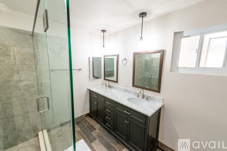 A bathroom with a glass shower stall and a vanity with a marble countertop.