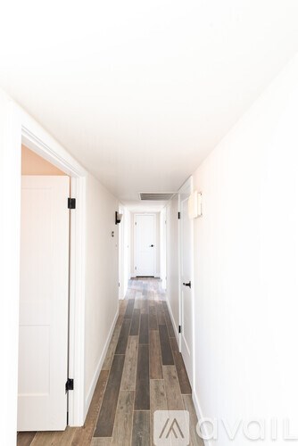 A hallway with white walls and a wooden floor.