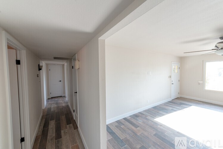 A long hallway with wood floors and white walls.