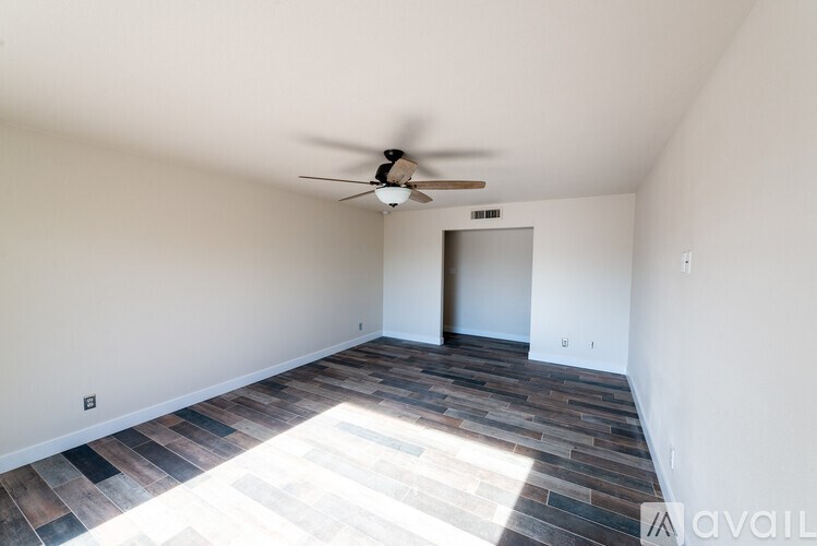 A room with a ceiling fan and a doorway leading to another room.