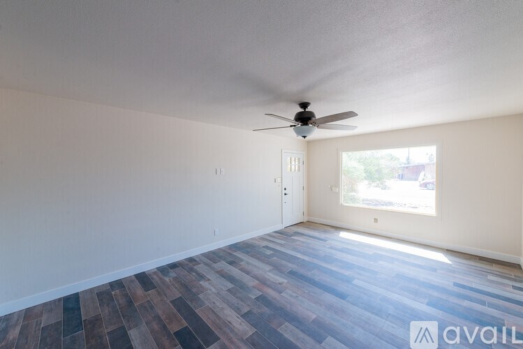 A room with a ceiling fan and a window letting in light.