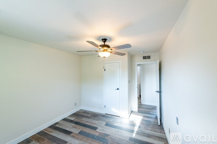 A room with a ceiling fan and a wooden floor.