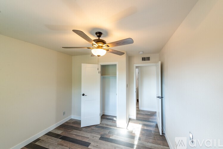 A room with a ceiling fan and wooden flooring.