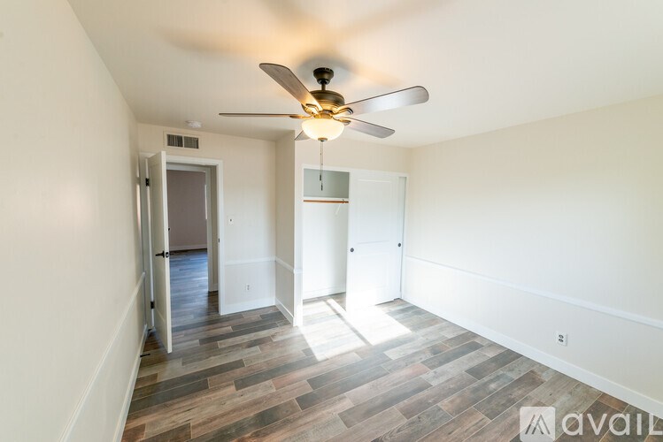A room with a ceiling fan and wooden flooring.