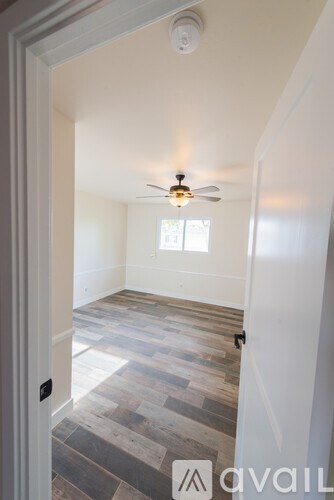 A room with a ceiling fan and wooden flooring.