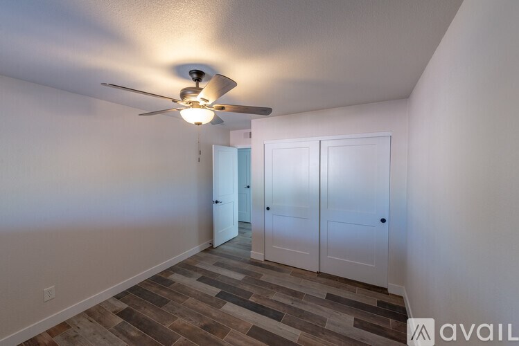 A room with a ceiling fan and a door leading to another room.