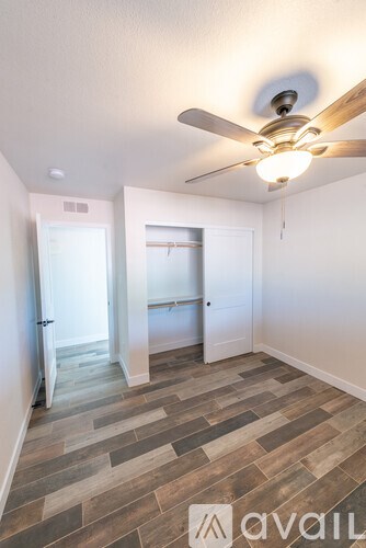 A room with a ceiling fan and wood flooring.