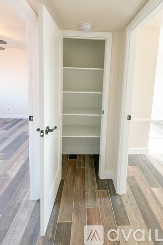 A white door with a glass panel is open to a hallway.