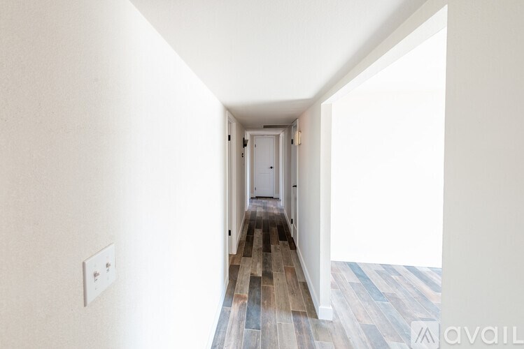 A hallway with a wooden floor and white walls.