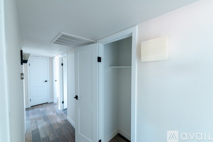 A hallway with a door on the right and a wall-mounted air vent.