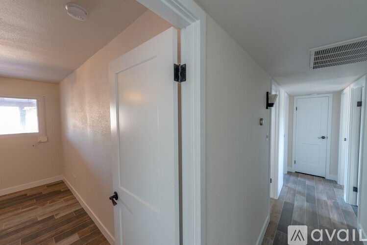 A hallway with a white door and a window on the left.