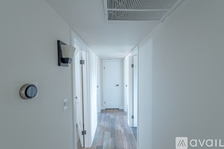 A long hallway with doors on both sides and a light switch on the wall.