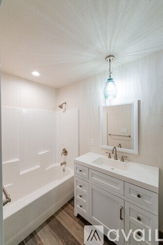 A bathroom with a white tub, sink, and vanity.