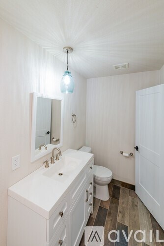 A bathroom with a white sink, toilet, and a mirror.