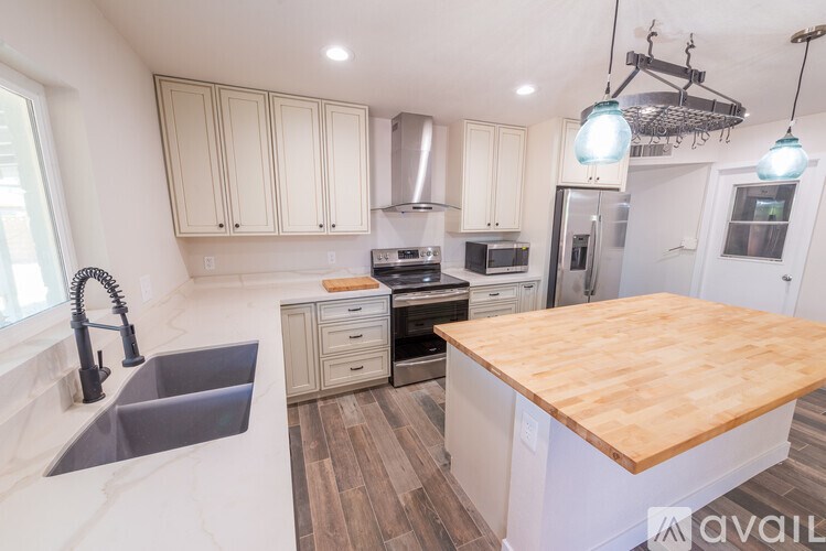 A kitchen with a wooden counter top and a sink with a black faucet.