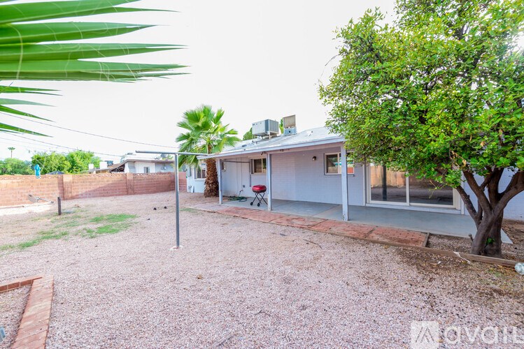 A house with a gravel yard and a tree in front.