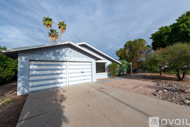 A house with a garage and palm trees in the background.