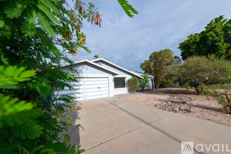 A house with a driveway and greenery in the foreground.