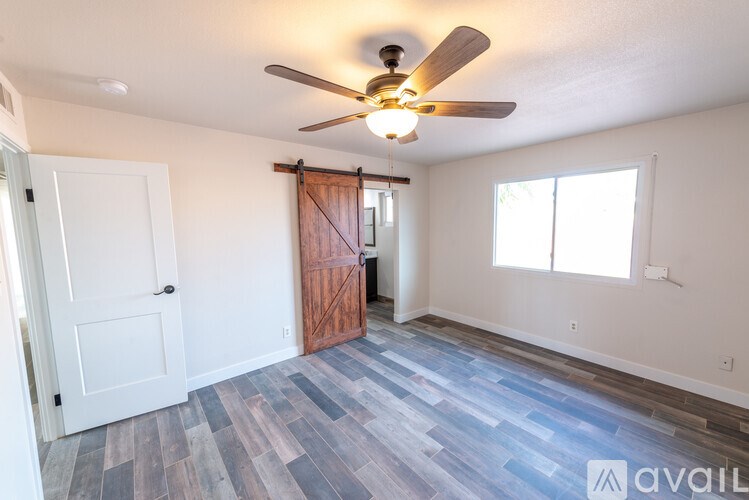 A room with a ceiling fan and wooden flooring.