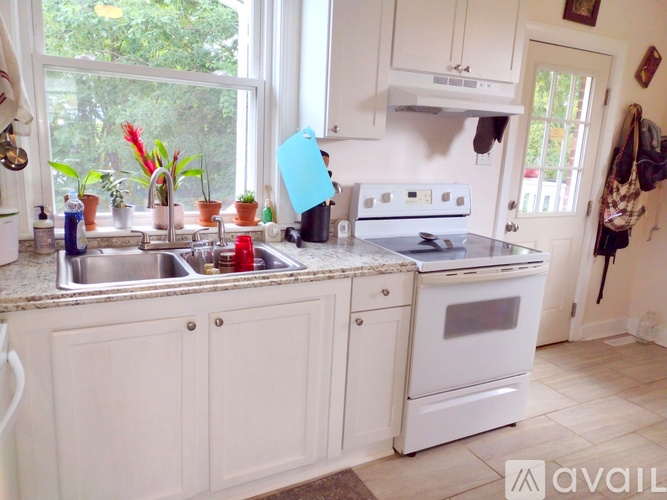 A kitchen with white cabinets and a white stove top oven.