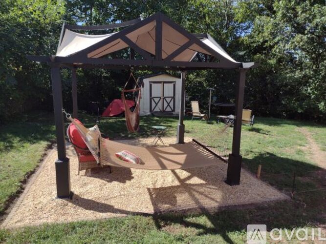 A gazebo with a swing set and a sandbox in the foreground.