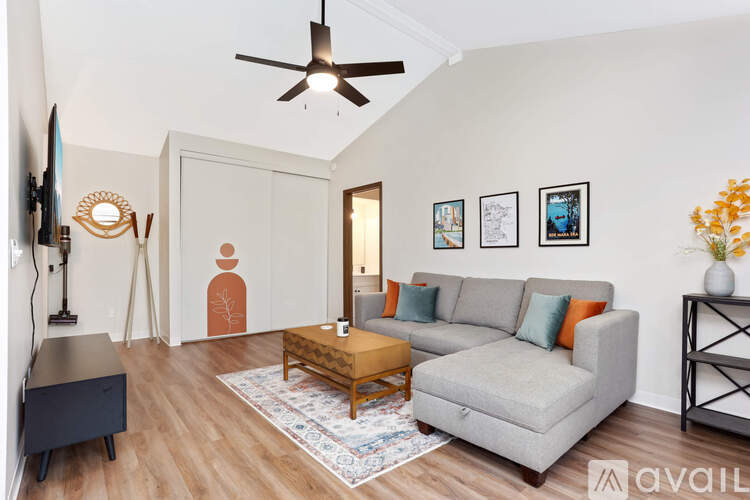 A living room with a grey couch, a wooden coffee table, and a ceiling fan.
