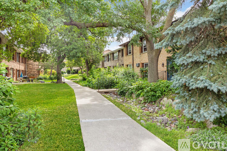 A pathway in a park with a grassy area on the left and a row of houses on the right.