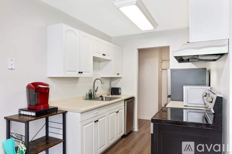 A kitchen with white cabinets and a black counter top.