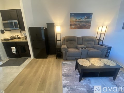 A living room with a grey sofa, a black coffee table, and a painting on the wall.