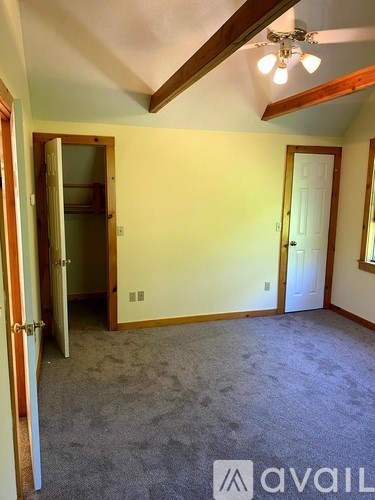 A room with a carpeted floor and a ceiling fan.