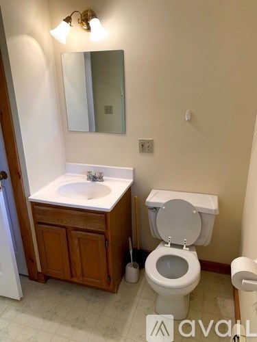A bathroom with a toilet, sink, and mirror.