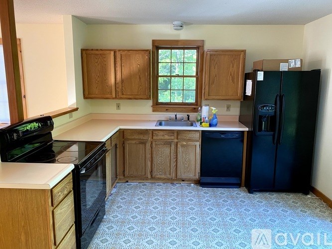 A kitchen with wooden cabinets and a black fridge.