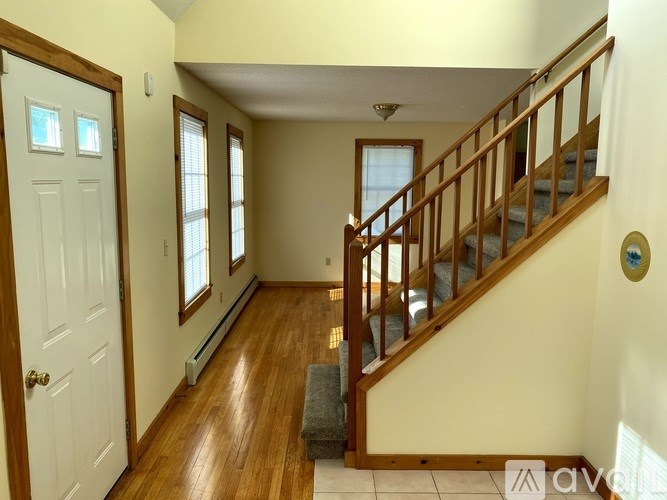 A hallway with a staircase and a door on the left.