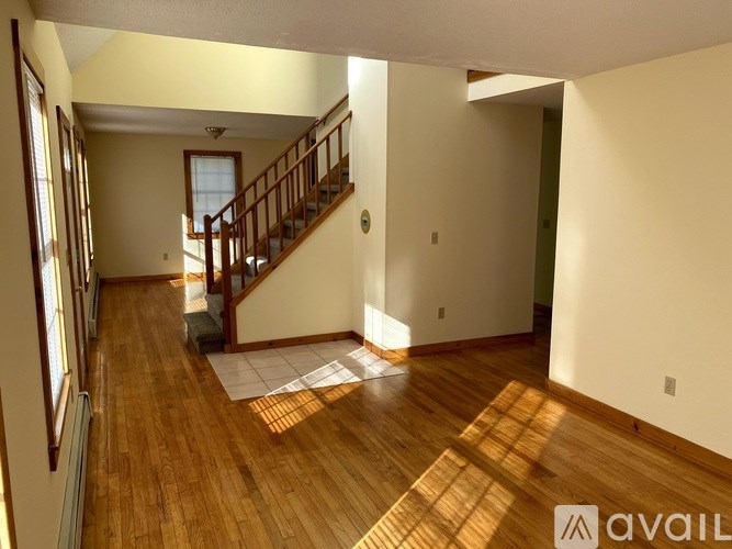 A spacious room with wooden floors and a staircase.