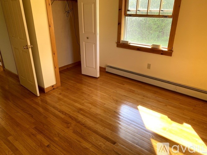 A room with wooden floors and a window letting in sunlight.