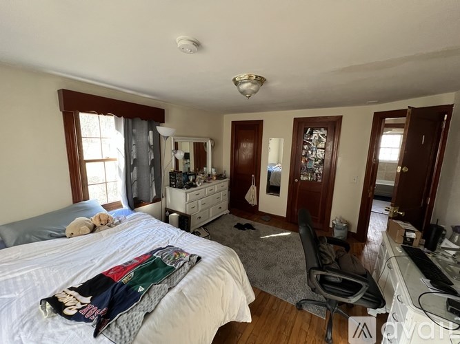 A bedroom with a bed, a chair, and a dresser.