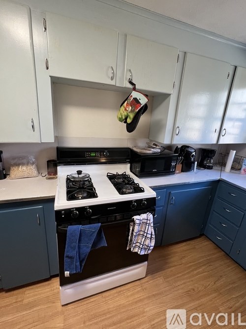 A kitchen with a black stove top and blue cabinets.