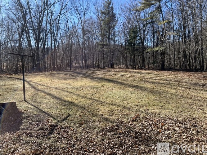 A field with trees in the background and a sign in the foreground.