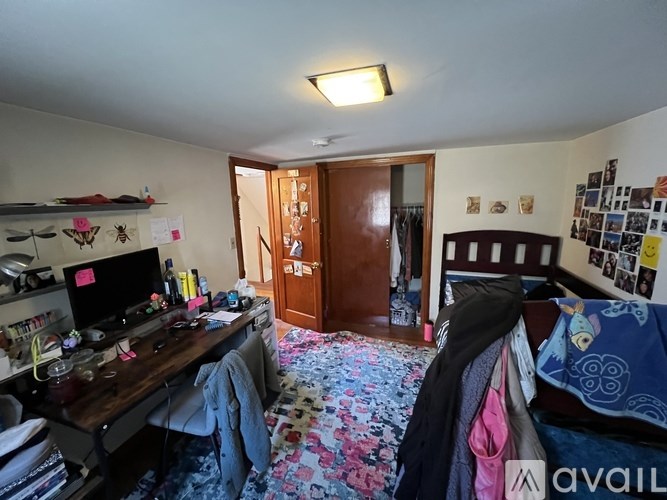 A room with a bed, desk, and clothing rack.