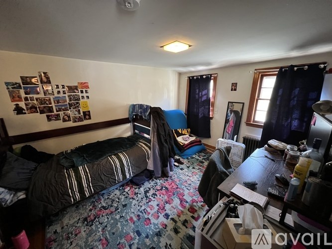 A messy bedroom with a bed, desk, and chair.
