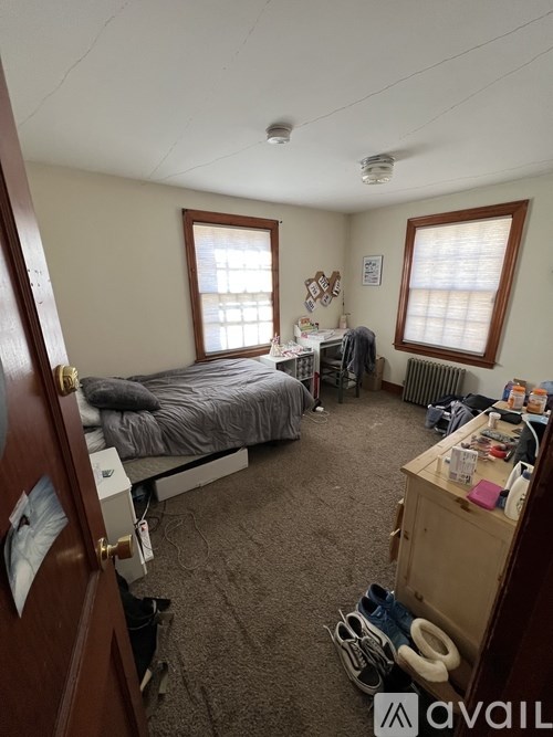 A bedroom with a bed, desk, and window.