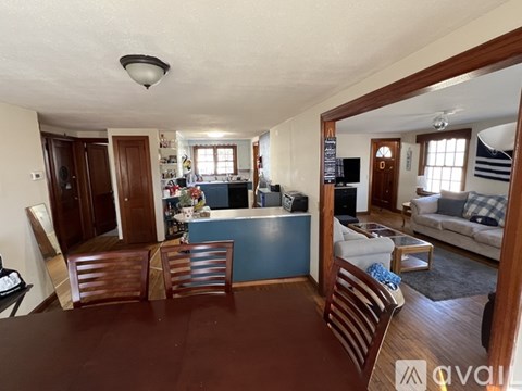 A living room with a blue couch and wooden chairs.