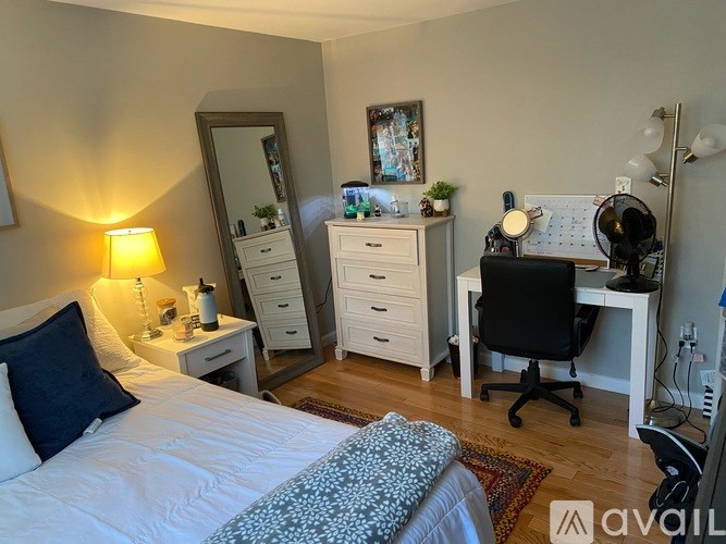 A well-lit bedroom with a bed, desk, and chair.