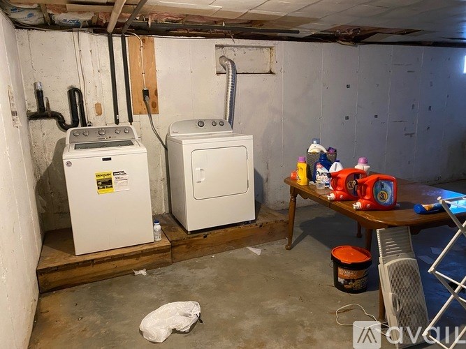 A room with two white appliances, a table with toys, and a fan.