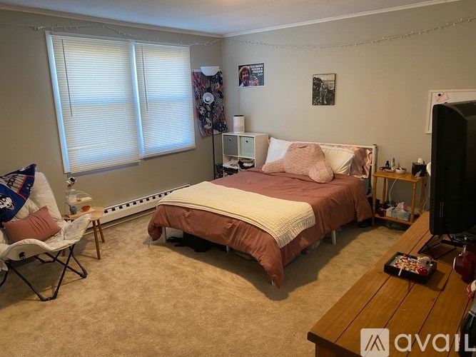 A bedroom with a bed, chair, and window.