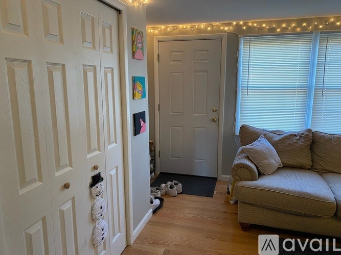 A room with a couch, a door, and a wall with pictures and lights.