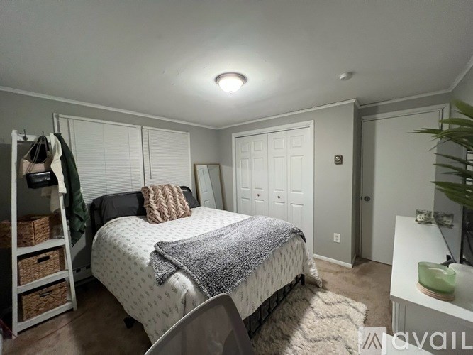 A bedroom with a bed, a chair, and a nightstand.