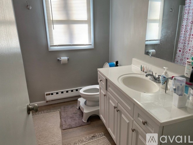 A bathroom with a toilet, sink, and window.