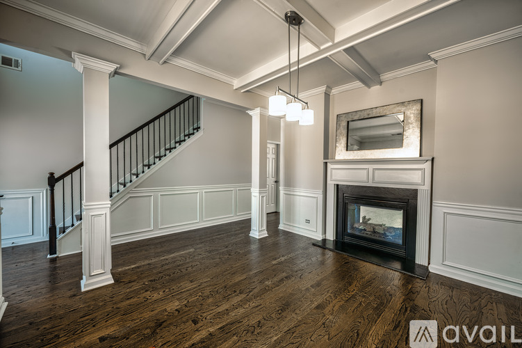 A spacious living room with a fireplace and a staircase.